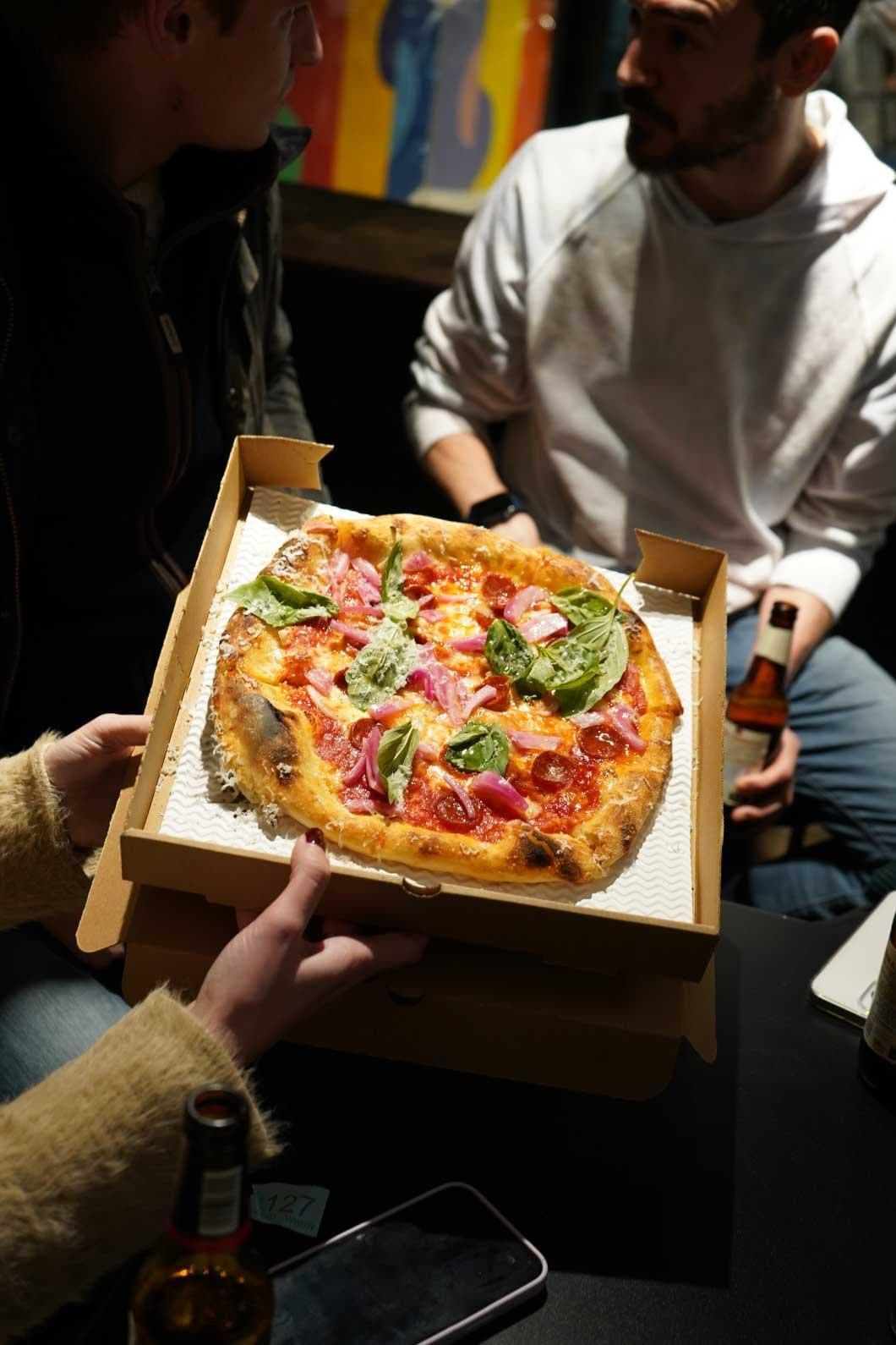 A pizza held up in its box