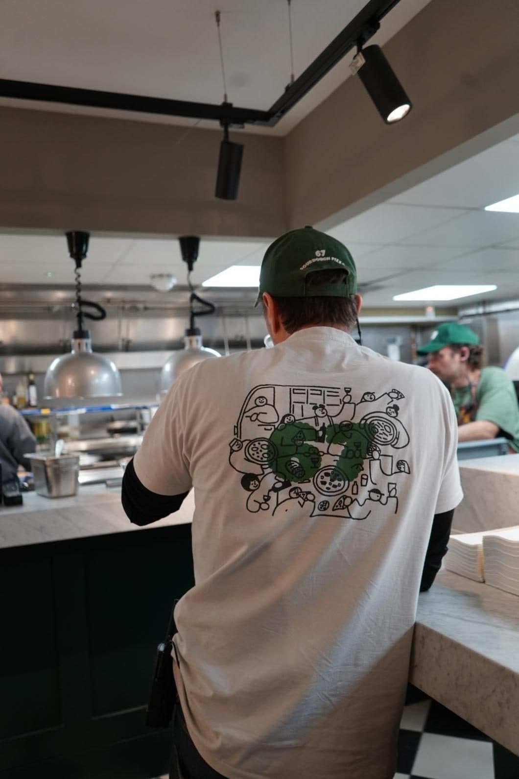 Chef at the pass in a 67 Sourdough t-shirt