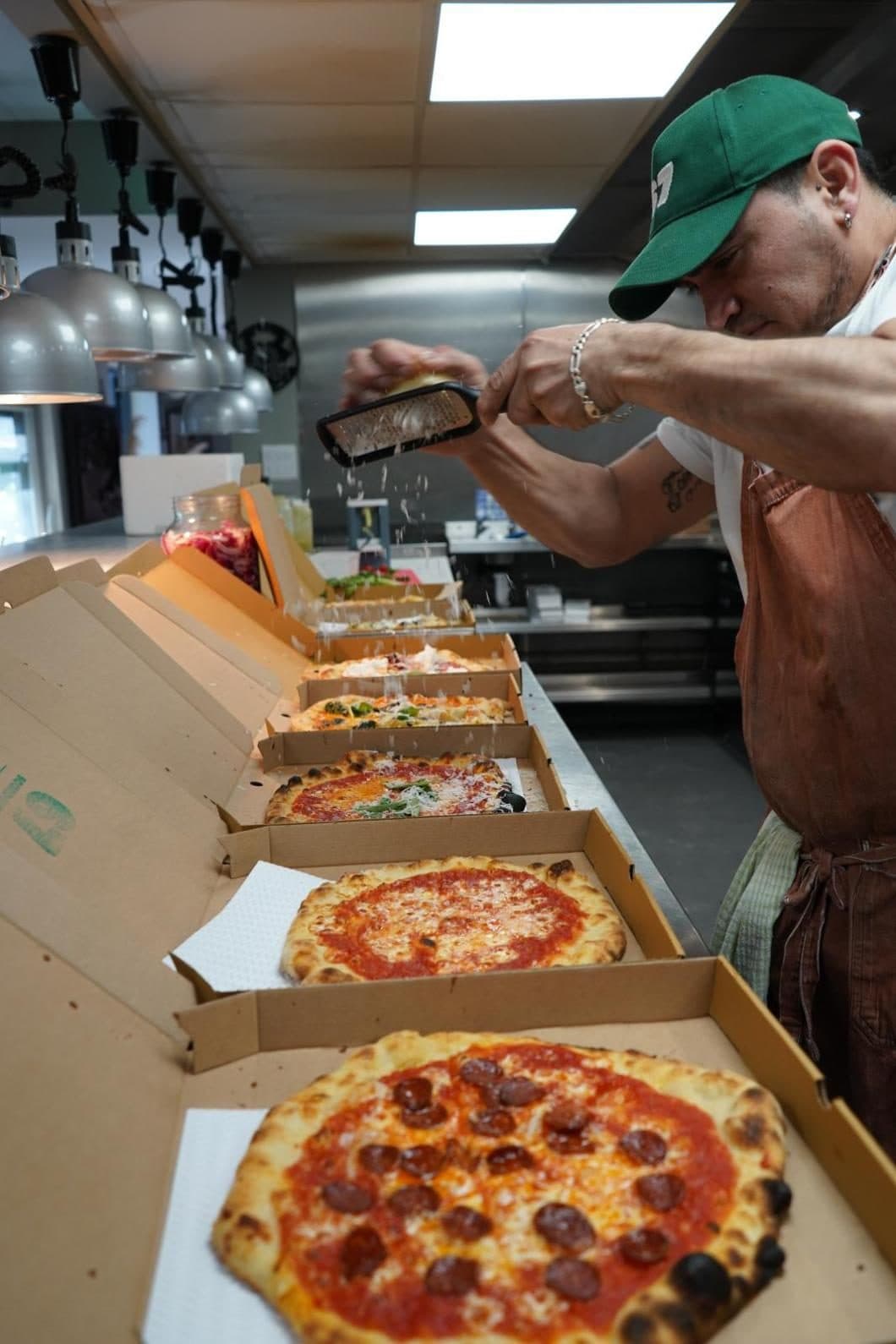 A row of pizzas boxed up at the pass