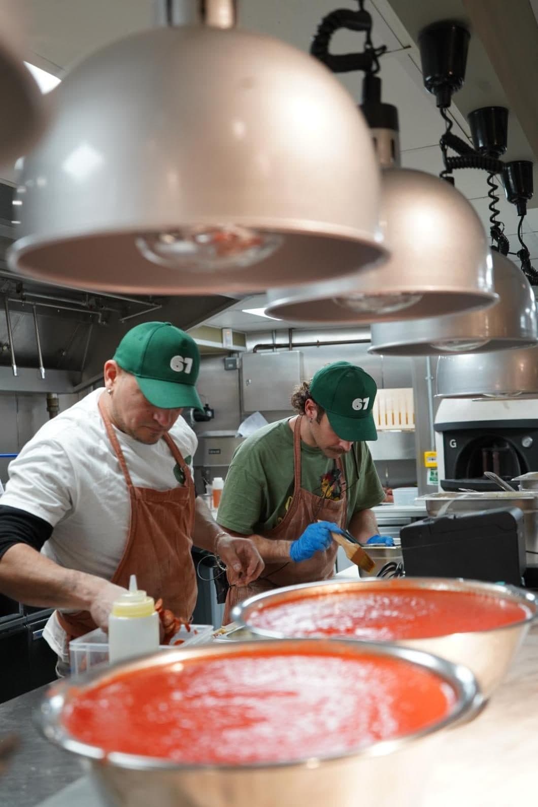 Chefs saucing bases under the heat lamps