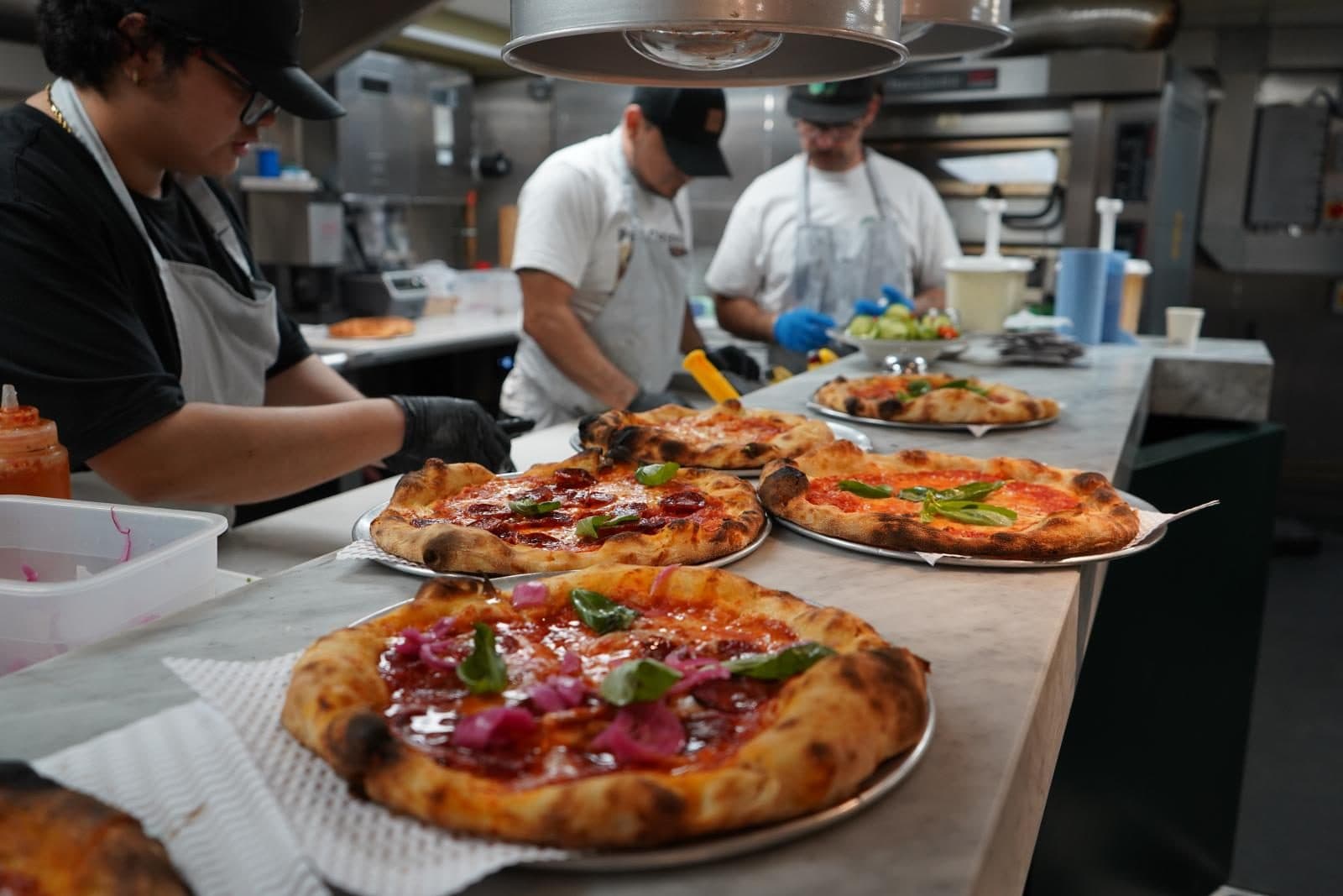 Chefs sending out pizzas from the open kitchen