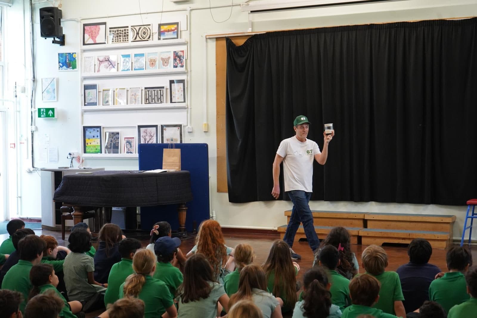 Cam talking to a hall full of school children in 67 t-shirts